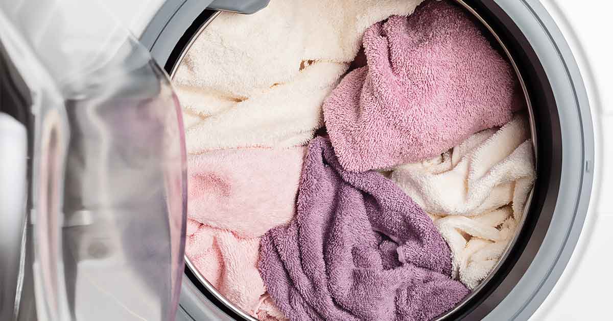 A washing machine filled with pink and purple towels.